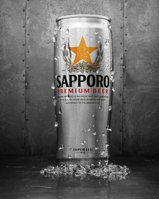 Sapporo Premium Beer can with condensation and ice crystals, set against a textured grey background. Product shot, food and beverage.