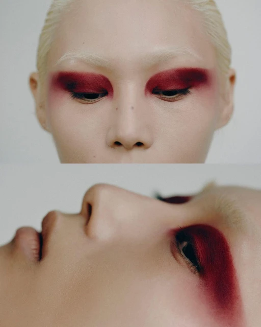 Close-up of a person with bleached hair and dramatic crimson eye makeup on a white background for beauty or fashion content.