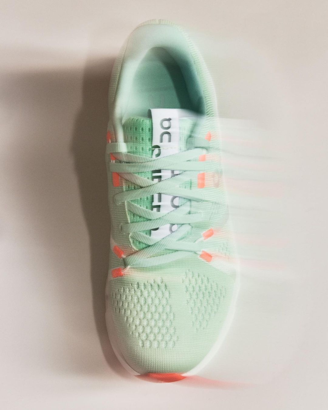 On brand running shoe in a light green color scheme with white laces, shot in a photo studio with bright light, product photography.
