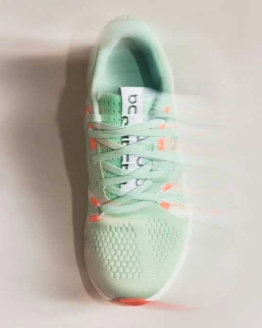 On brand running shoe in a light green color scheme with white laces, shot in a photo studio with bright light, product photography.