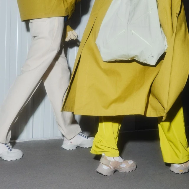 Two people wearing matching athletic shoes and contemporary casual wear walk on a concrete surface. Trendy fashion editorial.