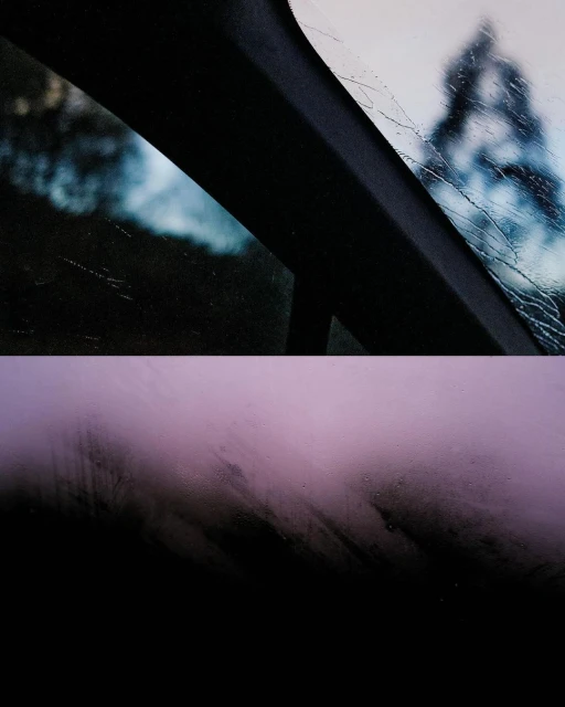 Abstract shot from inside car looking out at rain-covered windshield and blurred trees, with a lilac-colored panel and black bottom section.