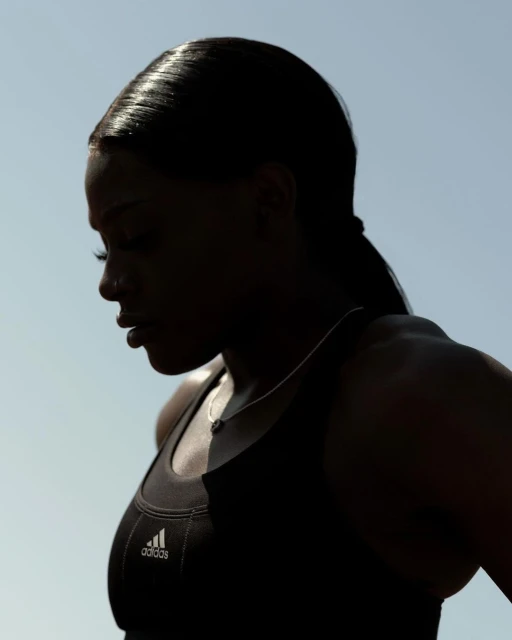 Close-up of a Black woman wearing an Adidas sports bra with hair pulled back in a ponytail, highlighting athletic apparel.