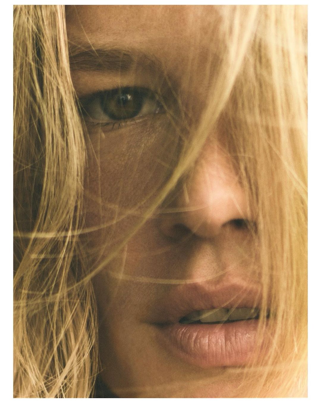 Extreme close-up portrait of a woman with blonde hair falling across her face shot by Annemarieke Van Drimmelen