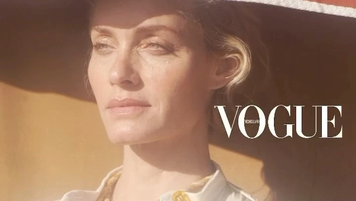 Close-up portrait of a woman wearing a wide-brimmed hat and white collared shirt under warm sunlight