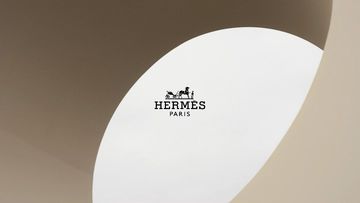 Minimalist composition with a white oval shape in a beige setting, featuring the 'HERMES PARIS' logo in black. Clean design.