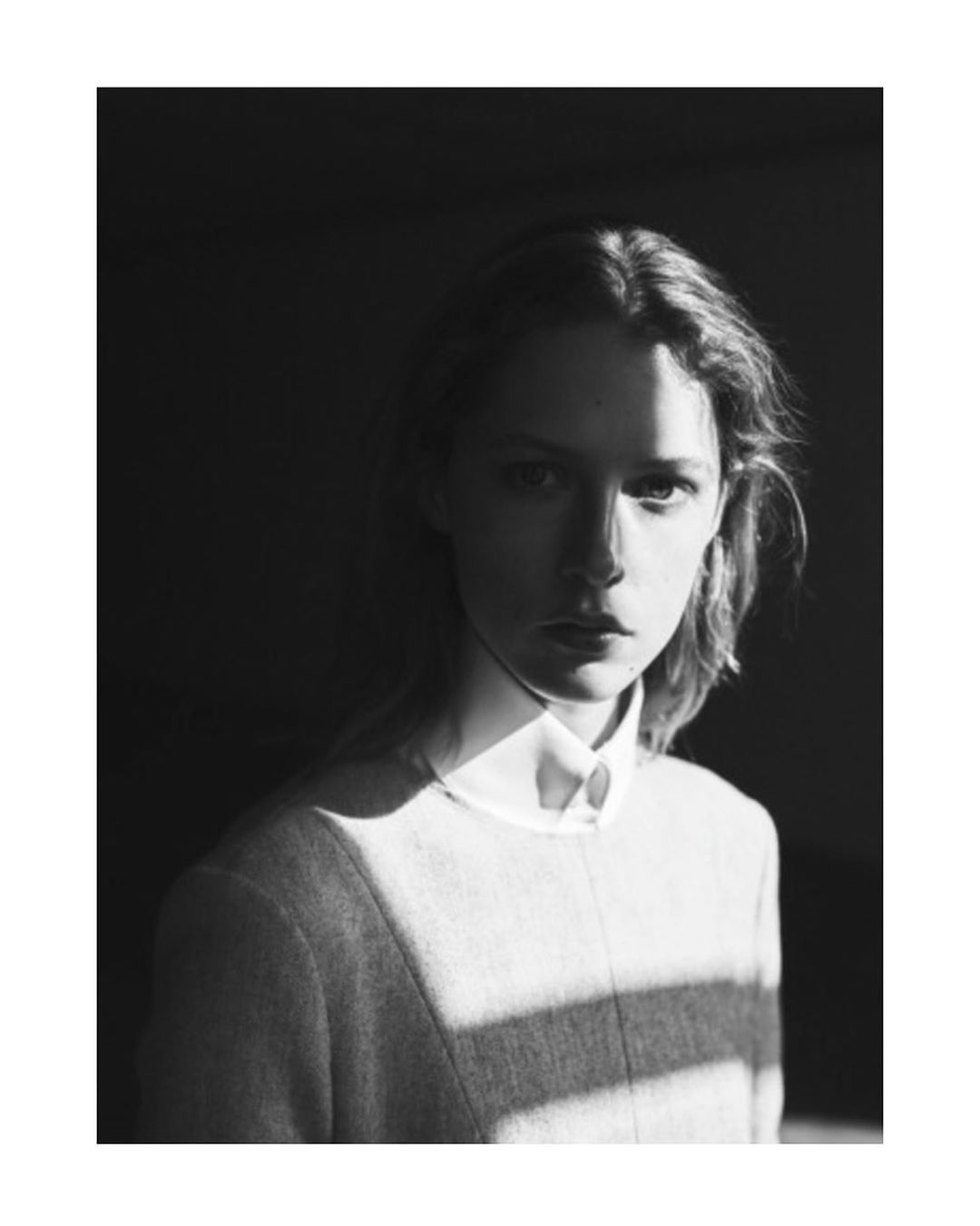 Portrait of a woman wearing a collared shirt under strong directional light by Annemarieke Van Drimmelen