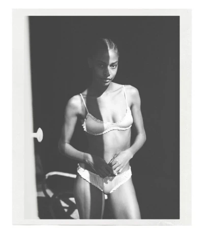 Monochrome studio portrait of a woman in lingerie with dramatic shadows, black background, and doorframe in the frame.