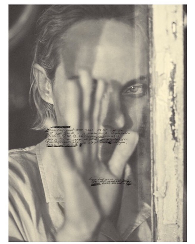 Monochrome portrait of a person peering through a hand covering their face, overlaid with handwritten text by Annemarieke Van Drimmelen.