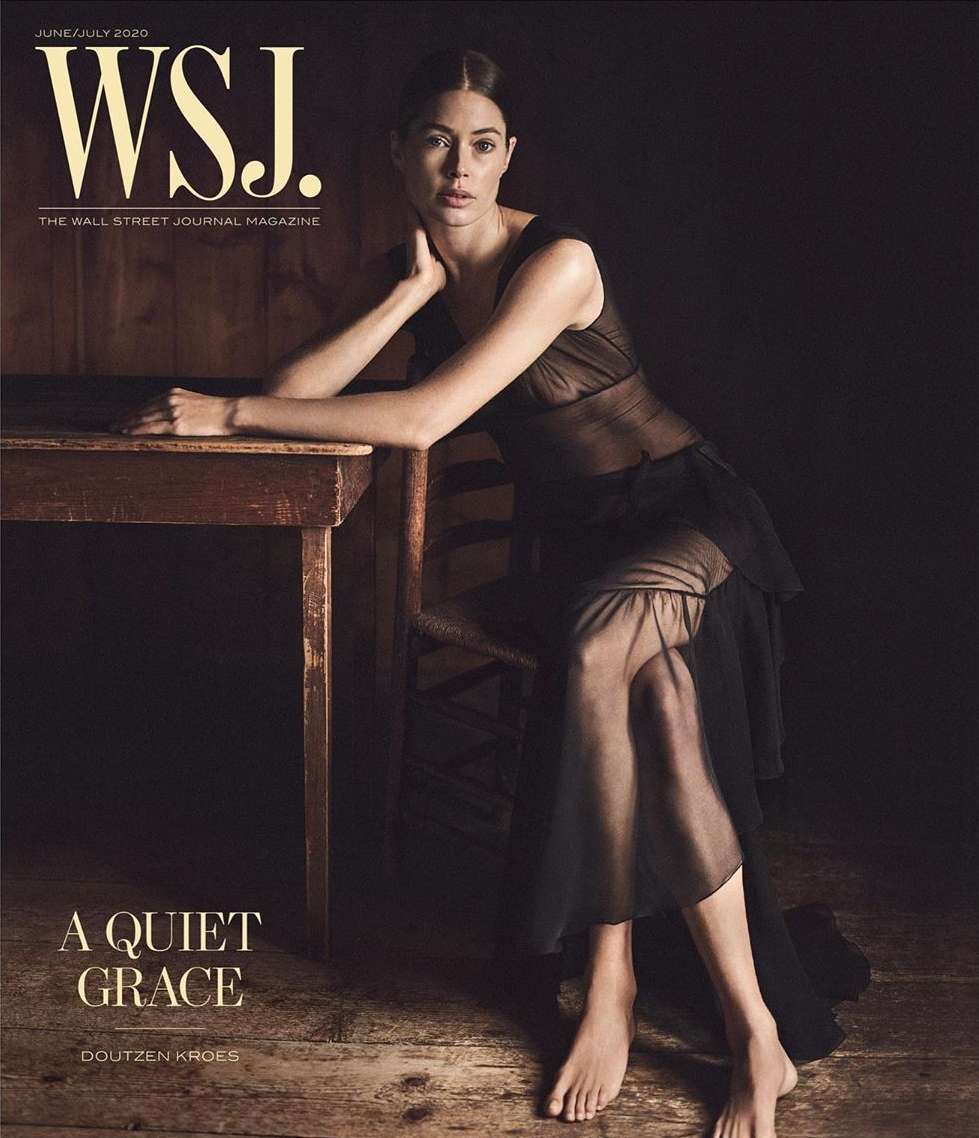 WSJ cover featuring a woman in a black dress seated at a wooden table, bathed in soft, diffused lighting, against a dark brown background.