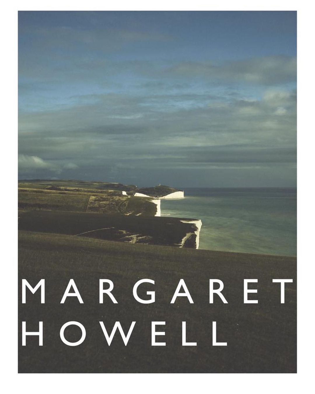 Landscape shot features white cliffs along a sea with a cloudy sky; below is displayed the text 'MARGARET HOWELL' in block letters.