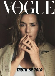 Close-up portrait of Kate Winslet with hands near face wearing a plaid coat photographed by Annemarieke Van Drimmelen
