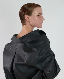 Model with slicked-back brown hair wearing a black leather jacket against a neutral studio background
