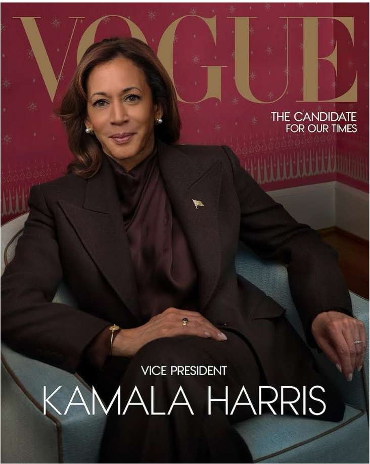 Portrait of Kamala Harris on a Vogue magazine cover wearing a brown suit and maroon shirt while sitting in a light blue chair.