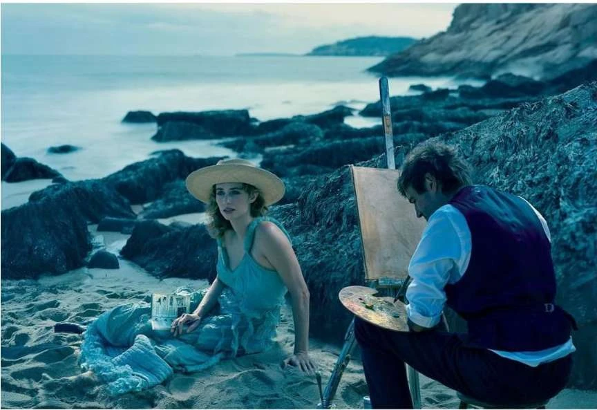 Woman in hat sits on beach near artist painting seascape with easel and palette of blues, set against ocean backdrop.