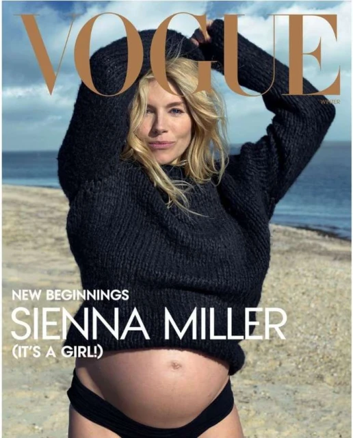 Sienna Miller poses on a beach for Vogue magazine cover. The pregnant woman wears a knit sweater and swimsuit bottoms in a sunny outdoor setting.