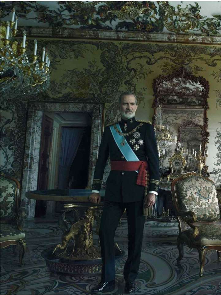 Full-length portrait of a man in formal military attire, adorned with medals and a sash, standing inside an elaborately decorated room.