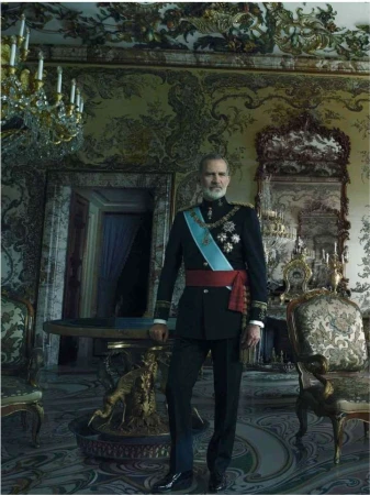 Full-length portrait of a man in formal military attire, adorned with medals and a sash, standing inside an elaborately decorated room.