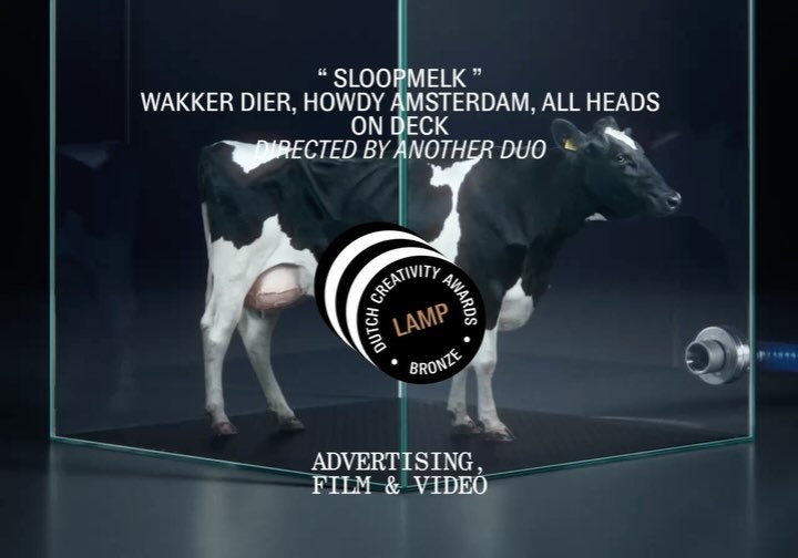 A black and white cow stands in a glass enclosure with text overlay and a Dutch Creativity Awards logo, promoting advertising for film and video.