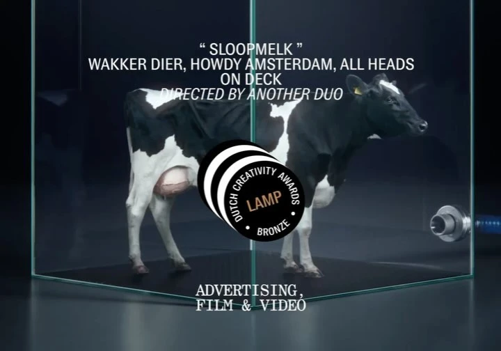 A black and white cow stands in a glass enclosure with text overlay and a Dutch Creativity Awards logo, promoting advertising for film and video.