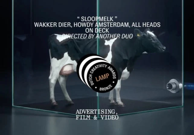 A black and white cow stands in a glass enclosure with text overlay and a Dutch Creativity Awards logo, promoting advertising for film and video.