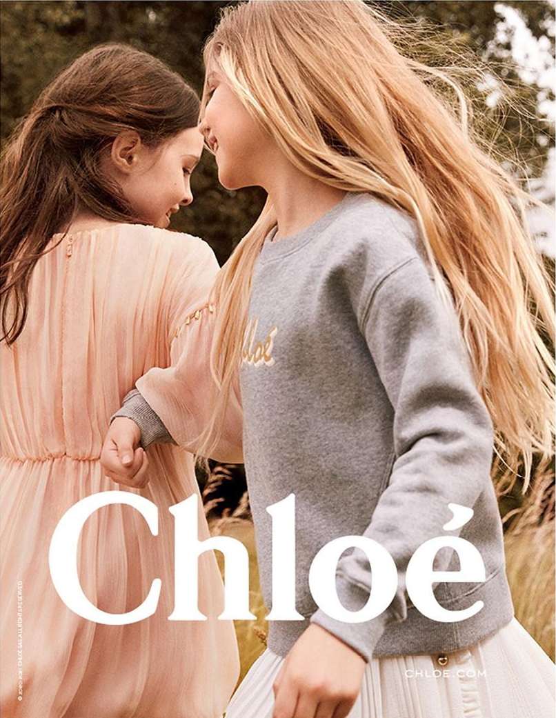 Two young girls in Chloe clothing standing closely in an outdoor setting, fashion advertisement with visible Chloe logo and brand name.