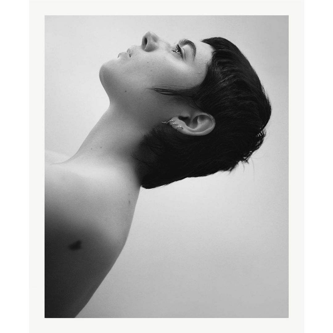 Black and white portrait of a woman with short dark hair in profile, tilted upward against a plain background.