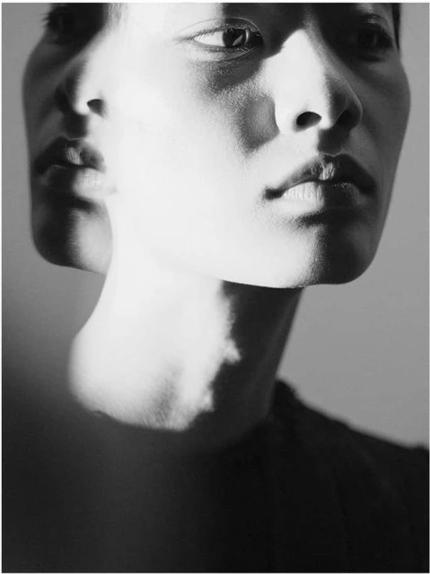 Monochromatic portrait of a person with layered facial features, shadows and highlights adding dimension and texture to the image.
