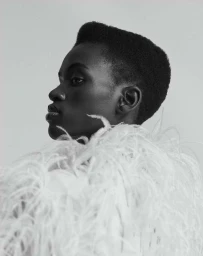 Black and white portrait of a black woman in profile wearing a feathered garment by Ansgar Sollmann