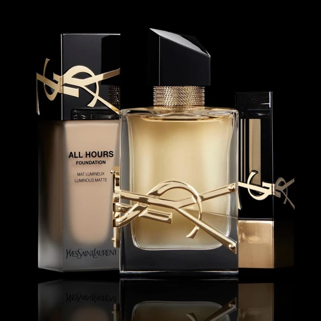 Still life shot of YSL beauty products including All Hours foundation, Libre eau de parfum, and Rouge Volupte Shine lipstick.