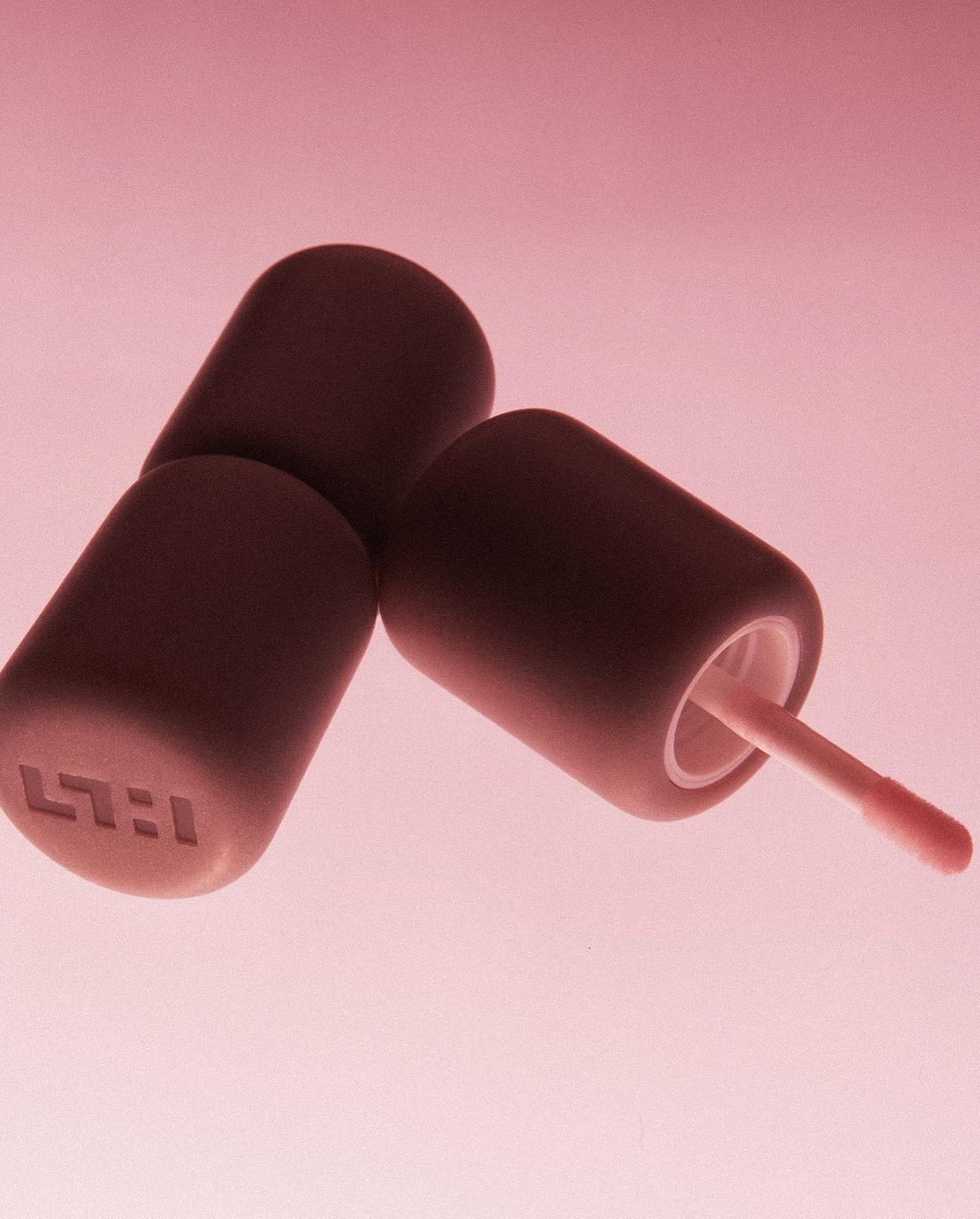 Three brown cosmetic applicators with light pink background offer a minimalist product shot for beauty or skincare promotions.