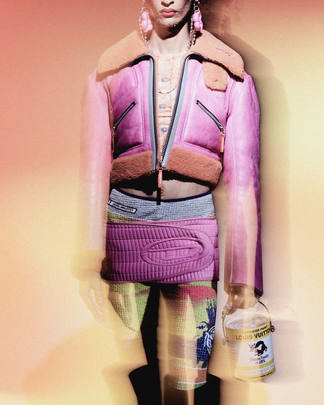 Model wearing a pink leather jacket with shearling collar and a pink quilted skirt holding a paint can, photographed by Anthony Arquier in Paris.