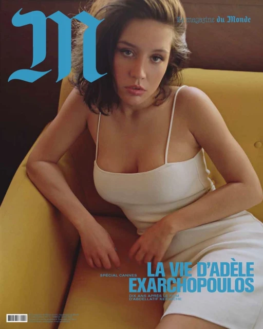 Magazine cover featuring Adèle Exarchopoulos in a white dress, seated on a yellow chair, with the magazine's logo in blue.