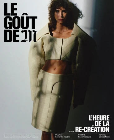 Fashion editorial image of a woman in a cream quilted jacket and skirt, posing in a studio with dramatic lighting and bold typography.