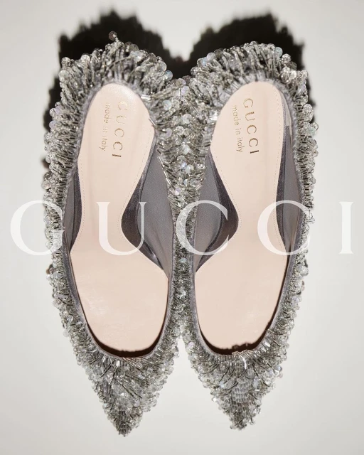 Close-up studio shot of a pair of silver-beaded Gucci heels with mesh and pale pink leather. Elegant designer fashion footwear.