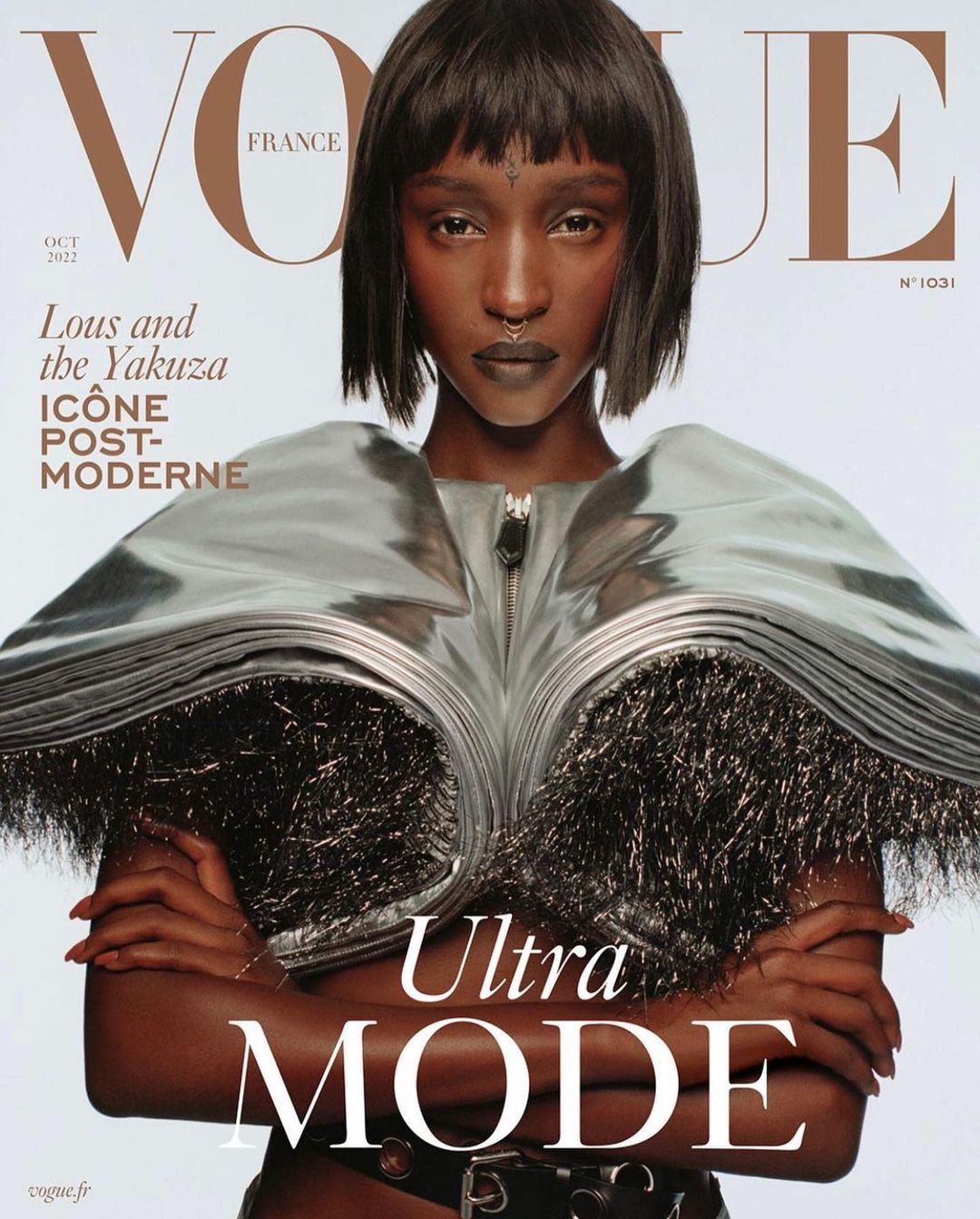 Vogue France cover featuring a model with dark hair and a silver metallic outfit with bold, modern text overlay and a white background.