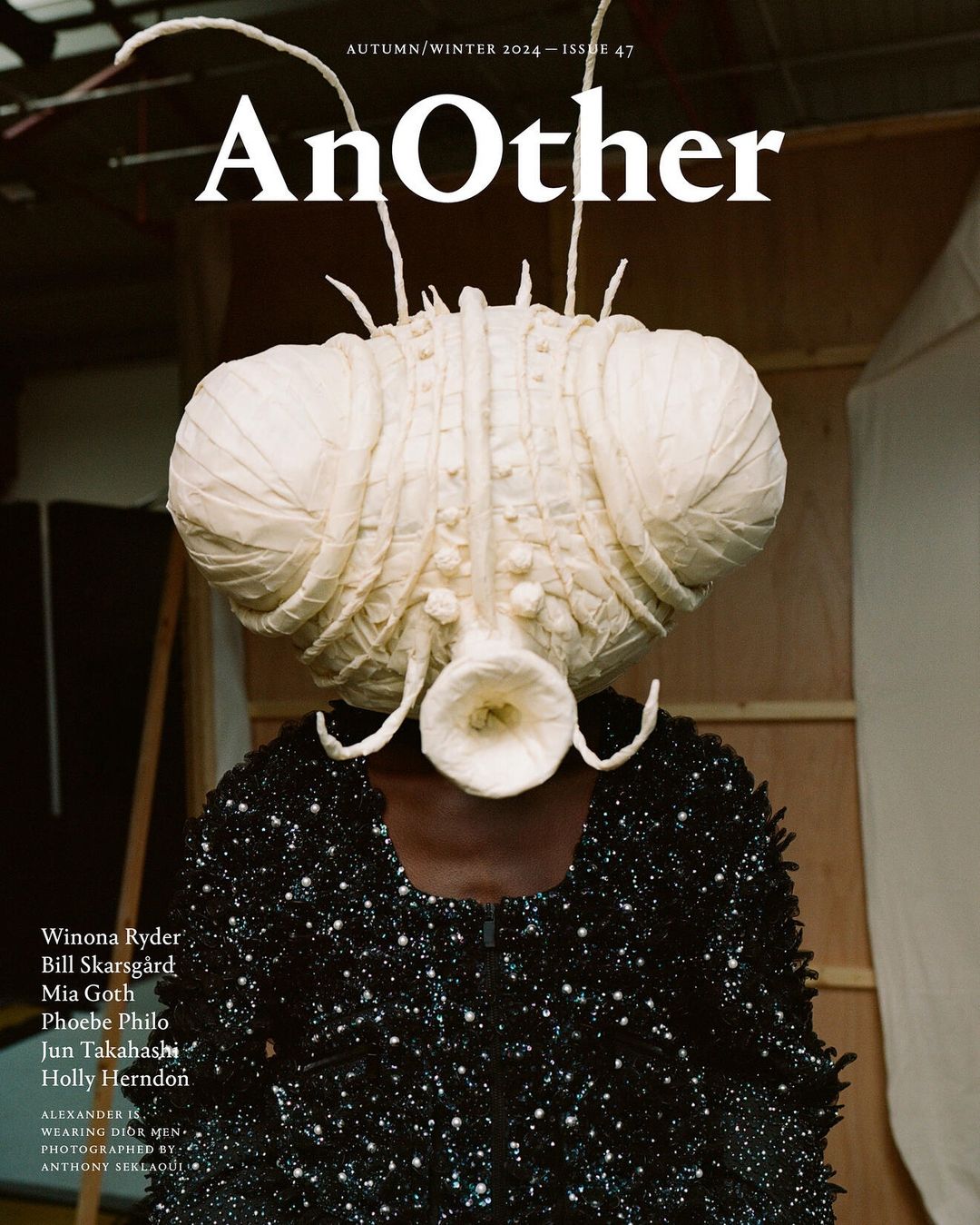 Magazine cover featuring a person wearing a large, elaborate, otherworldly headpiece and a black, sequined top against a studio backdrop.