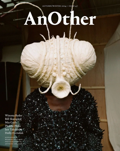 Magazine cover featuring a person wearing a large, elaborate, otherworldly headpiece and a black, sequined top against a studio backdrop.
