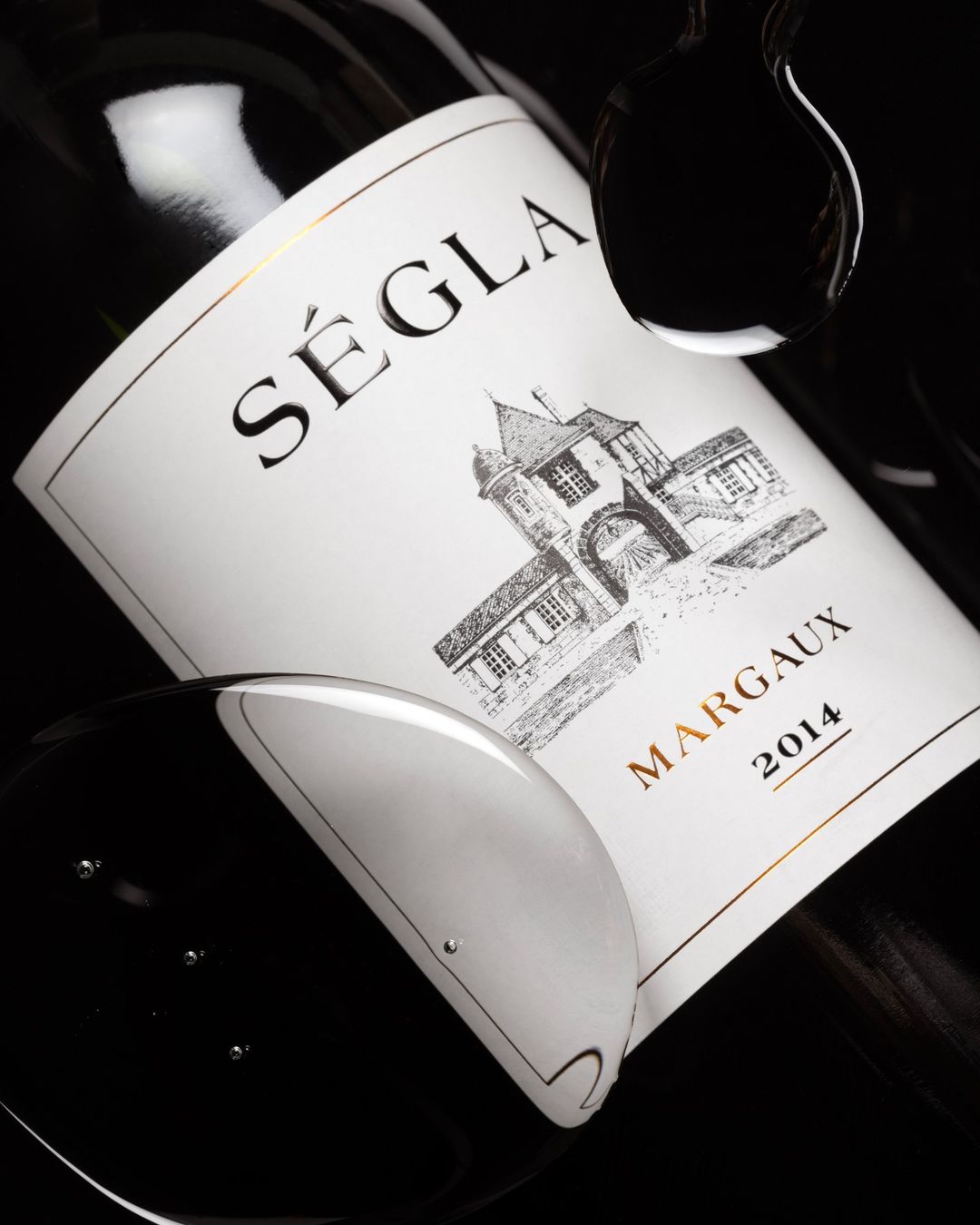 Close-up of a bottle of Séglà Margaux 2014 wine with water droplets against a black background, showcasing its label details and elegance.