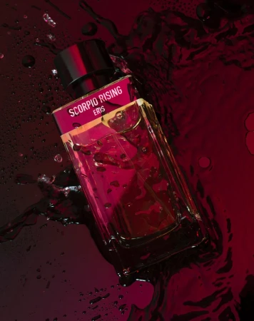 Eris Scorpio Rising perfume bottle on a reflective dark surface with water droplets, product shot, beauty industry advertising.
