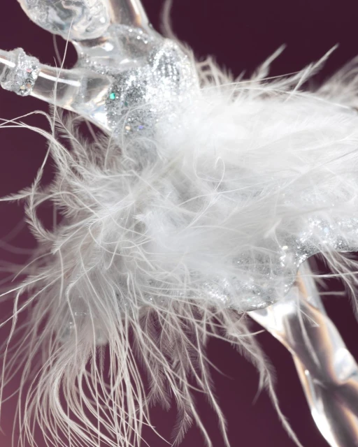 Close-up of a glittery ballerina figurine adorned with white feathers, set against a solid dark mauve background.