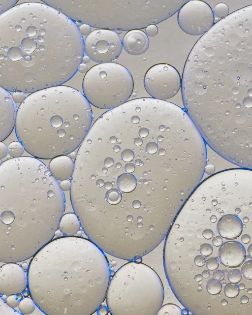 Close-up of numerous translucent liquid droplets with pale interior and blue edges, creating a visually intriguing abstract design.