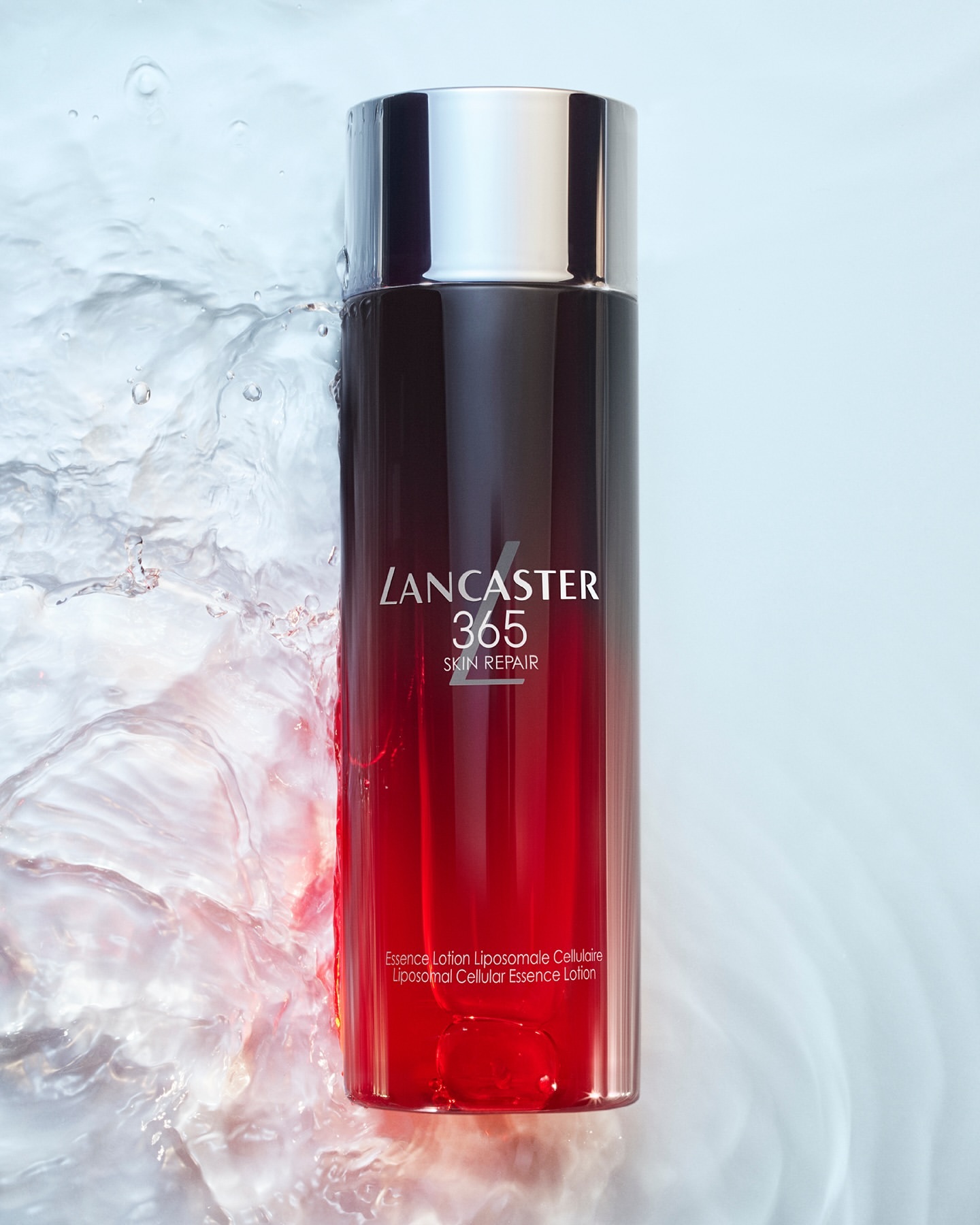 Lancaster 365 Skin Repair essence lotion bottle with black and red gradient, silver cap, and water splashes in a beauty shot.
