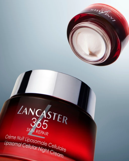 Product shot of Lancaster 365 Skin Repair night cream, featuring a glass jar with a red and silver lid against a light blue gradient background.