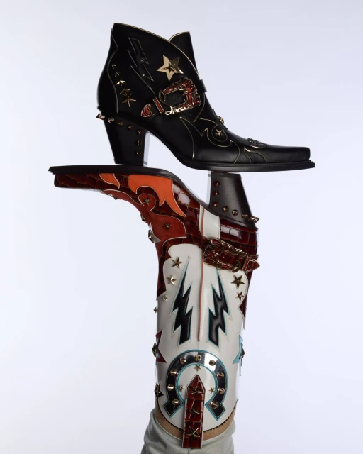 Two ornately decorated leather ankle boots are displayed against a white background, showcasing a blend of Western and edgy designs.