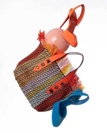 Striped woven tote bag with orange and blue high heel slingbacks floating in a white studio setting. Fashion-forward footwear and accessories.