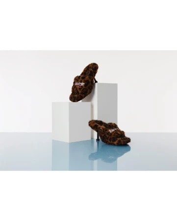 Two high-heeled shoes with a leopard print design displayed on white cube platforms against a gradient blue and white background.