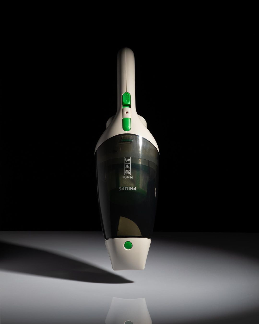 A cordless Philips handheld vacuum cleaner is centered against a dark background, illuminated with light, showcasing its design.