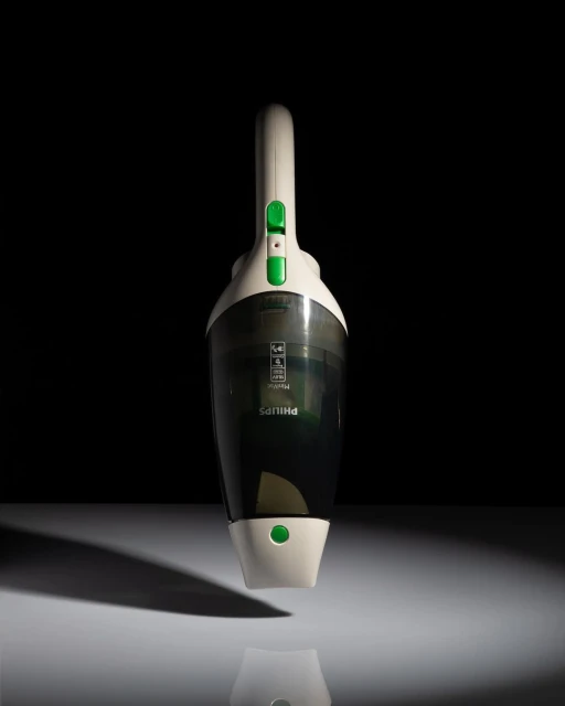 A cordless Philips handheld vacuum cleaner is centered against a dark background, illuminated with light, showcasing its design.