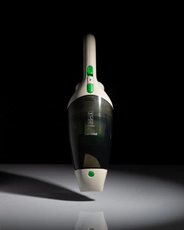 A cordless Philips handheld vacuum cleaner is centered against a dark background, illuminated with light, showcasing its design.